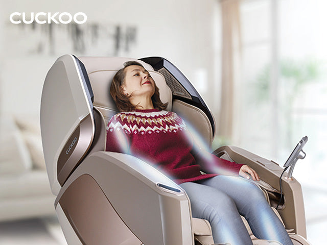 Cuckoo luxury massage chair with a woman relaxing comfortably in a modern living room setting.